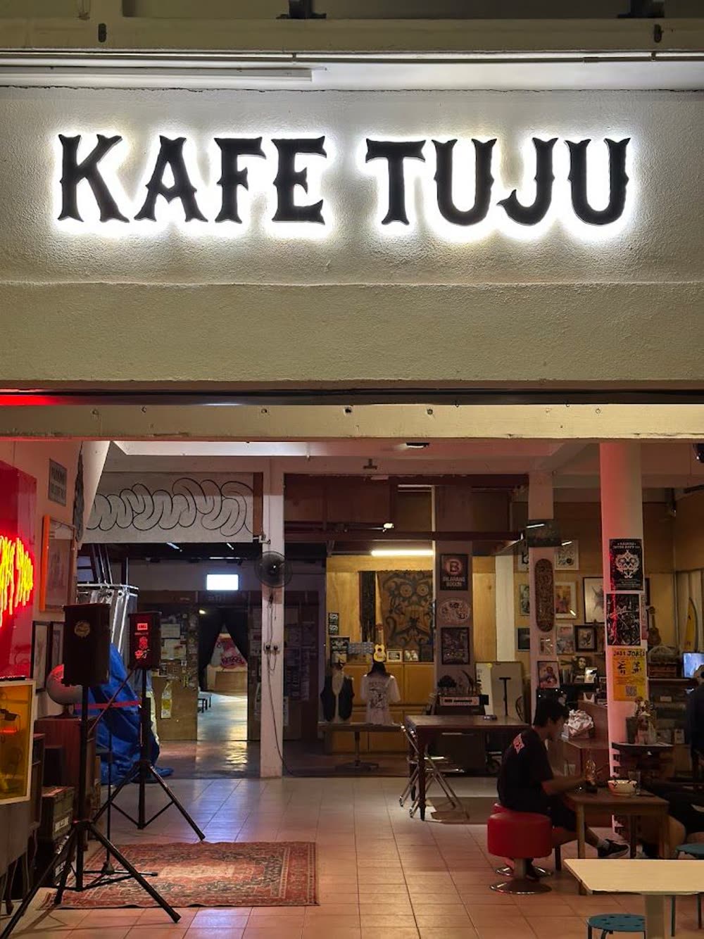 The Kafe Tuju sign above the entrance, with the warmly lit interior behind