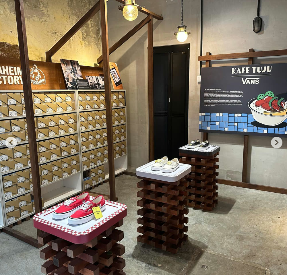 Shoe display on wooden plinths beside the Kafe Tuju and Vans board inside the cafe